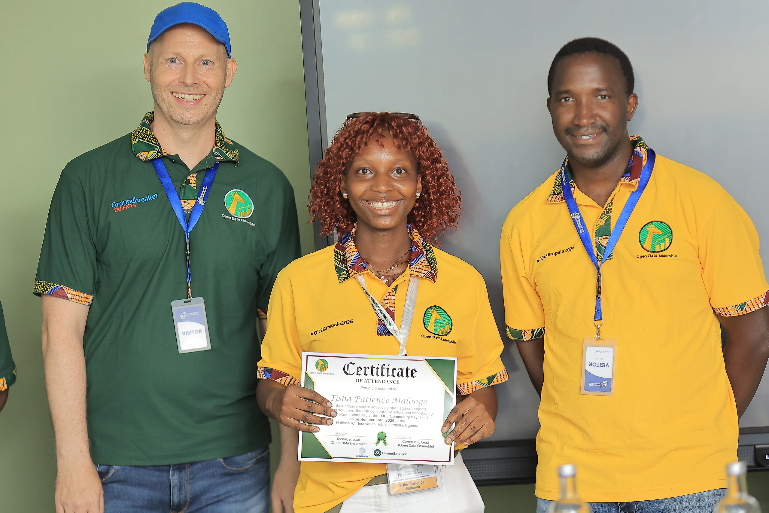 A participant holds up her certificate between two facilitators.