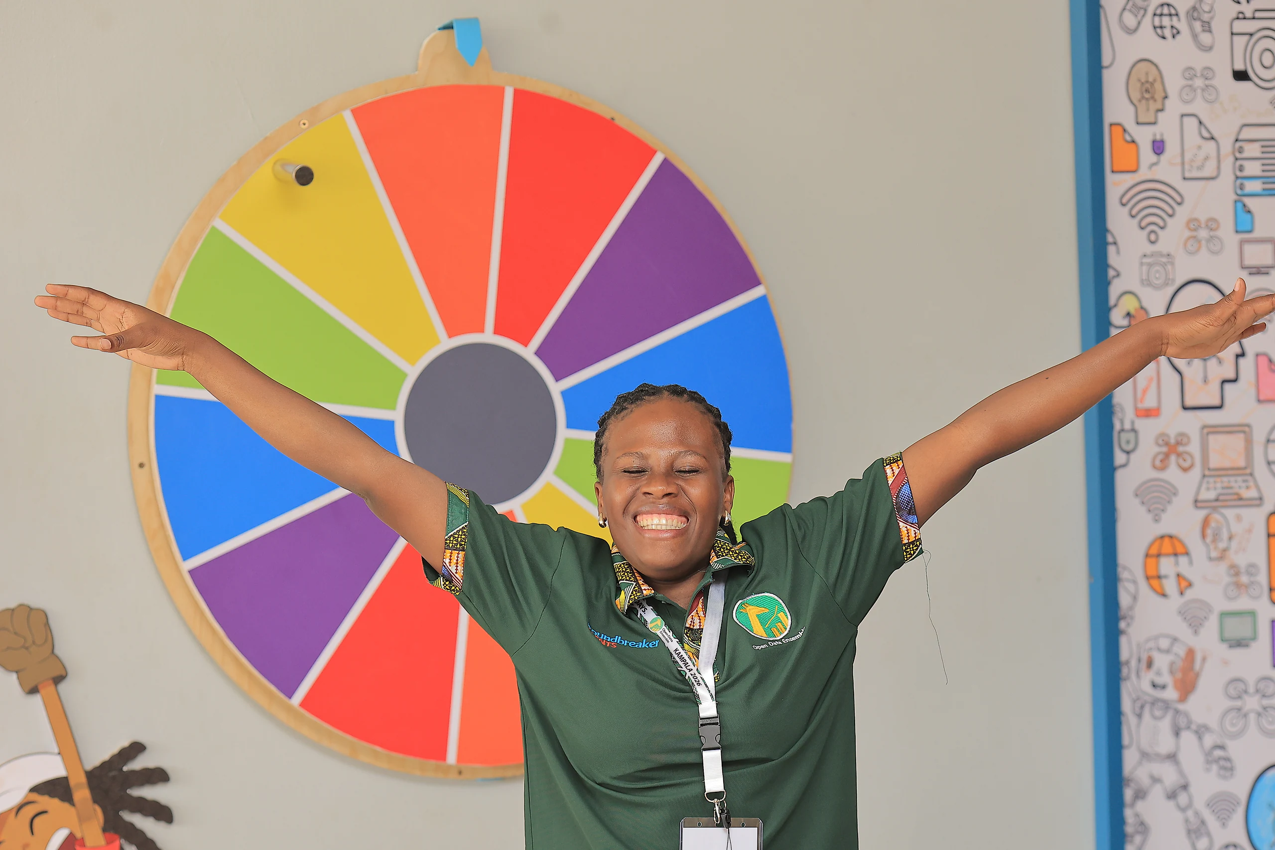 A participant throws her arms wide in front of a colourful prize wheel.