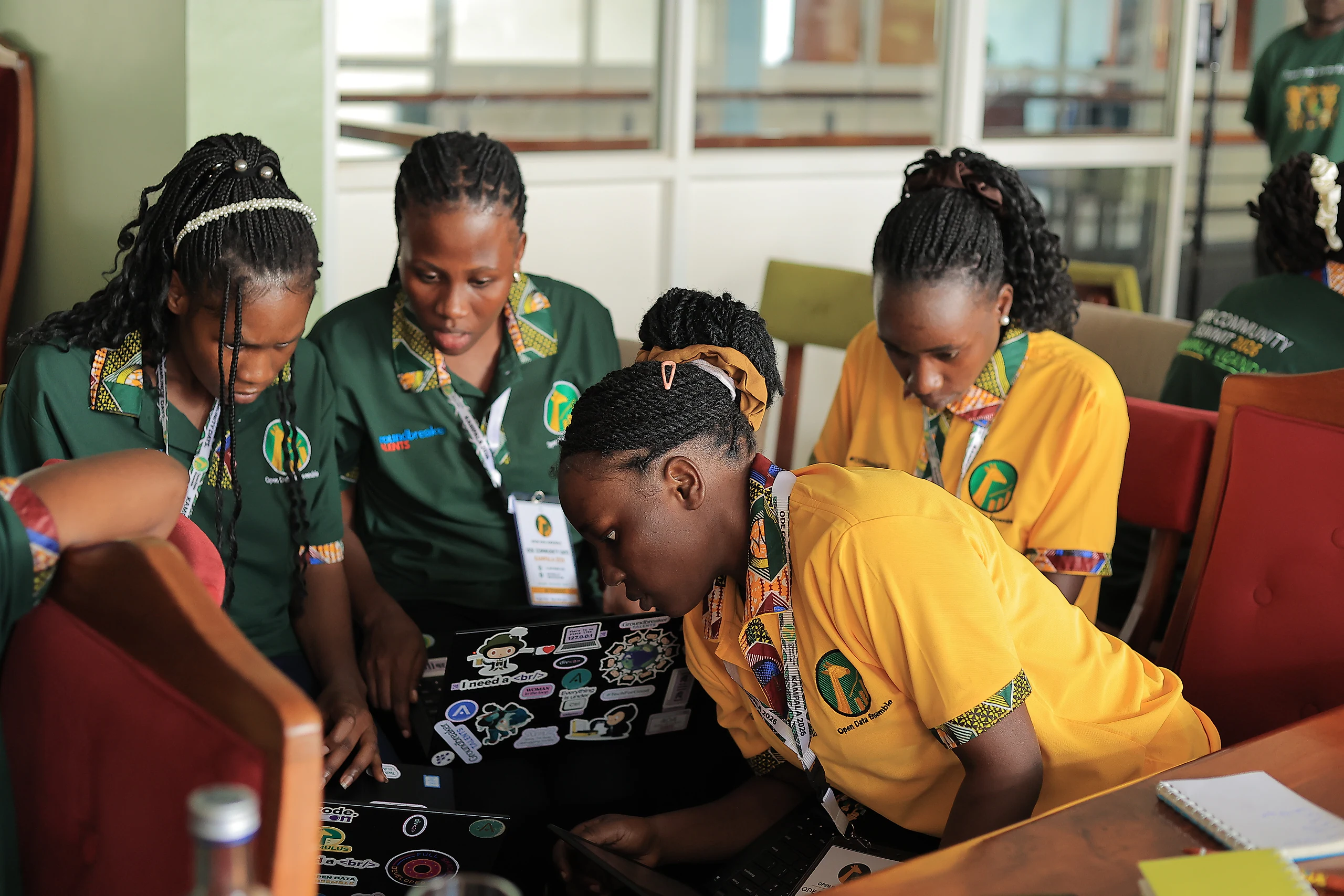 Participants lean in over a sticker-covered laptop.