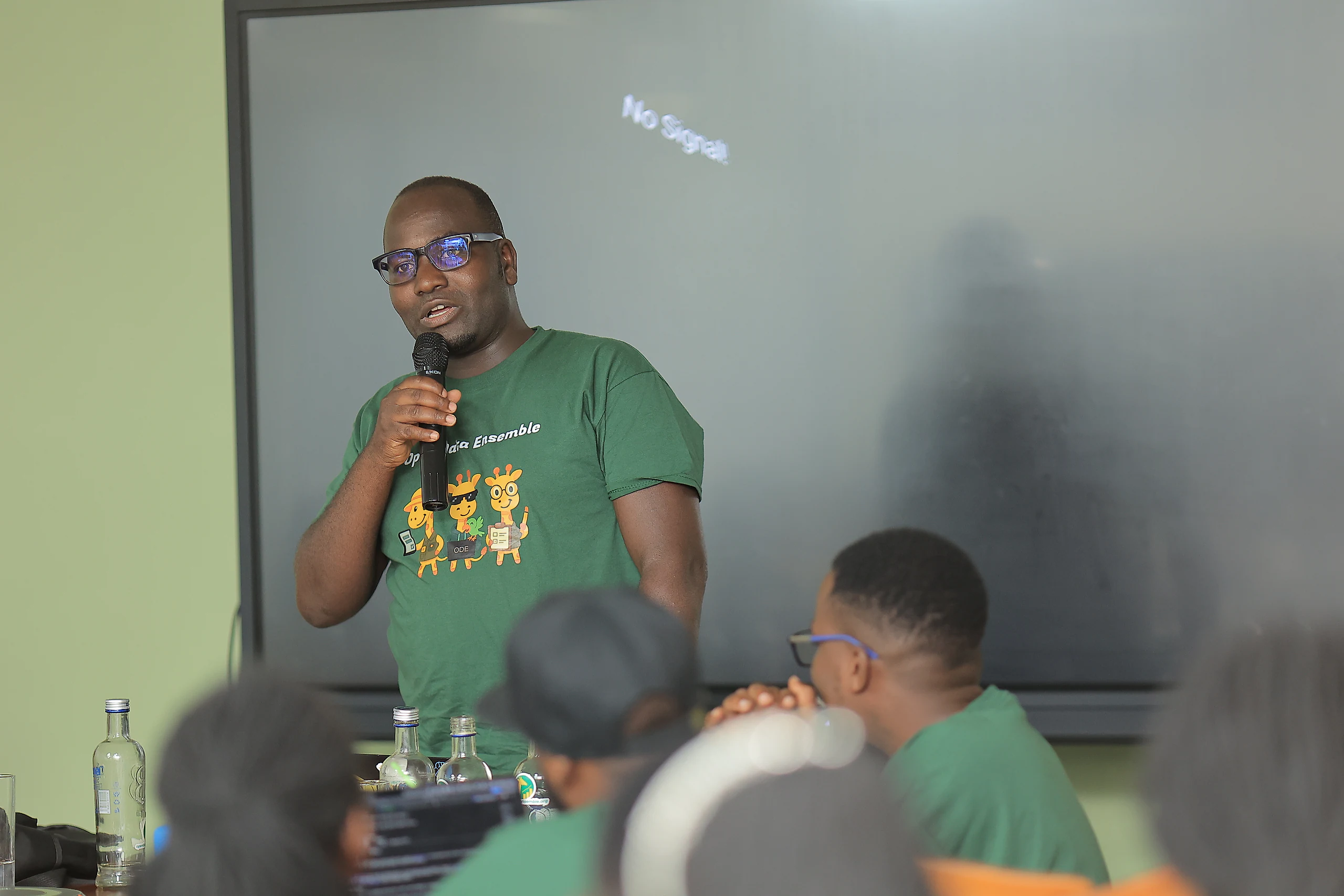 A speaker in an Open Data Ensemble t-shirt talks to the room.