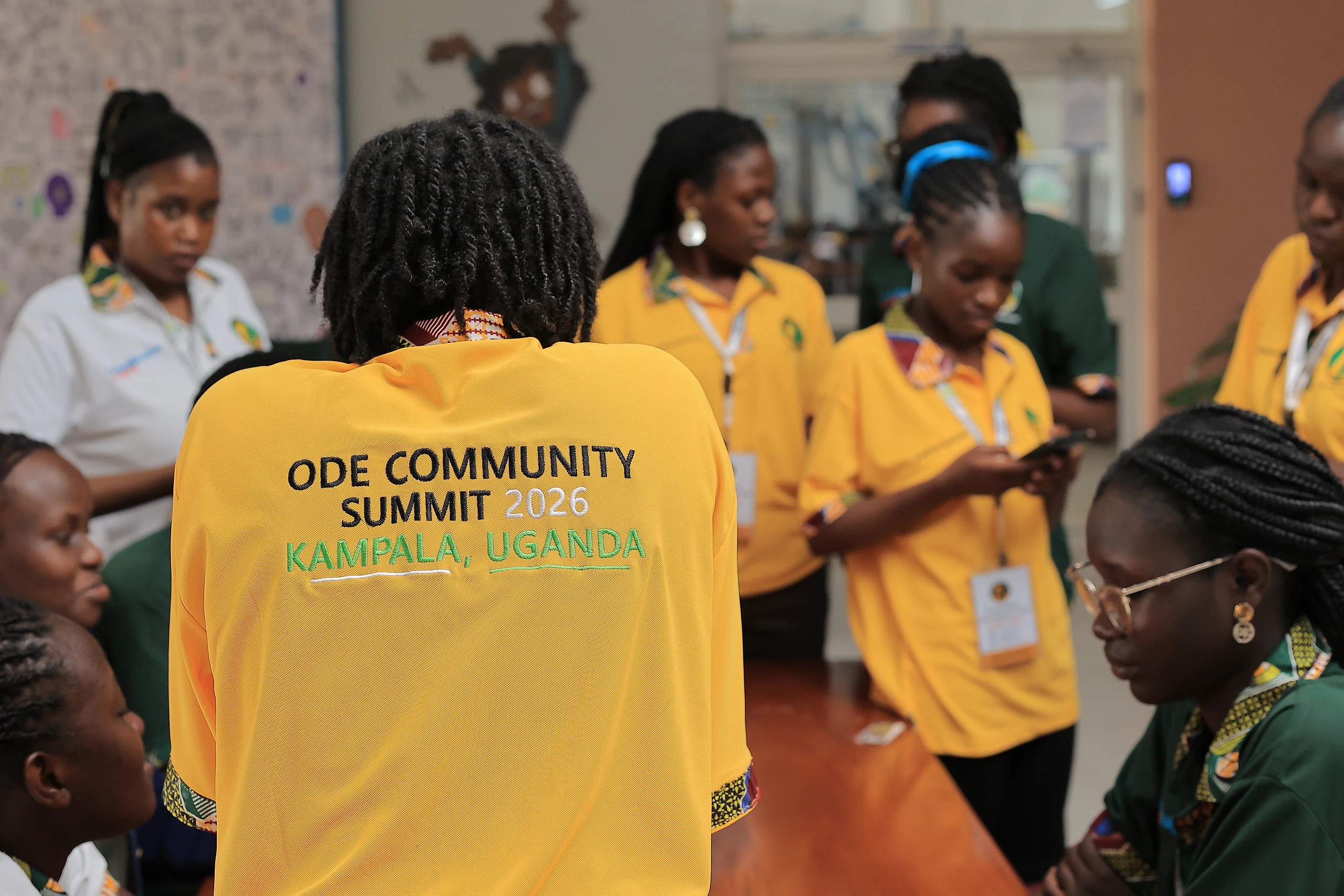 The back of a gold polo embroidered “ODE Community Summit 2026, Kampala, Uganda”.
